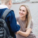 Foto: Shutterstock. Bildet viser en mor som hjelper sin sønn med skolesekk.